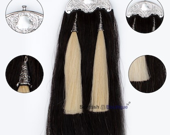 Puede incluir: Un par de sporrans de kilt de pelo de caballo negro y blanco con hebillas y borlas plateadas. Los sporrans cuelgan de una cadena plateada.