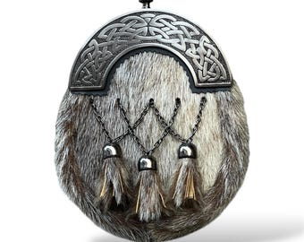 Könnte beinhalten: Ein traditioneller schottischer Sporran mit einem silbernen keltischen Knotendesign und drei Quasten. Der Sporran ist aus hellbraunem Fell gefertigt.