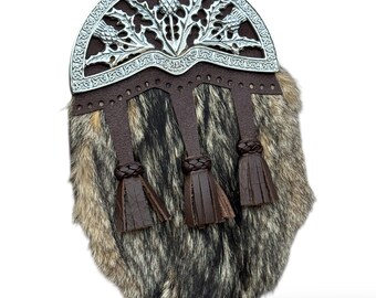 Könnte beinhalten: Ein traditioneller schottischer Sporran mit einem silberfarbenen Cantle mit Distelmotiven. Der Sporran hat eine braune Lederklappe mit drei Lederquasten und einen Fellkörper in Braun-, Schwarz- und Grautönen.