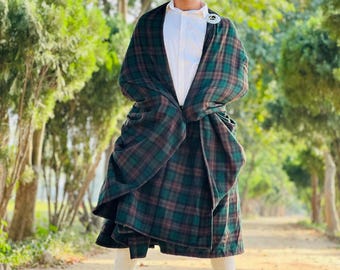 Peut inclure: Un homme portant une chemise blanche, un chapeau noir et un kilt écossais vert et marron. Il se tient sur un chemin de terre avec des arbres en arrière-plan.