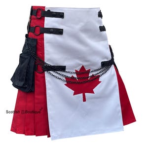 Op de afbeelding: Een kilt met een rood en wit ontwerp met een groot rood esdoornblad. De kilt heeft zwarte bandjes, een zwarte ketting en een zwart zakje. Het onderste gedeelte is geplooid rode stof.