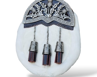 Può includere: Un sporran di pelliccia bianca con un cantle decorativo in metallo argentato con disegni di cardi. Lo sporran ha tre nappe argentate con accenti in pelle bordeaux, sospese da catene. Il cantle è attaccato a un supporto in pelle marrone scuro.