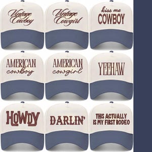 May include: Nine baseball caps with cream-coloured front panels and navy blue brims. Each cap displays text in a brown, vintage font. Phrases include "Vintage Cowboy", "American Cowgirl", and "This is my first rodeo". A stylish accessory for casual wear.