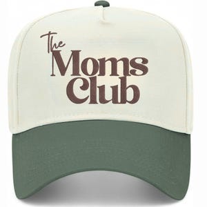 Peut inclure: Casquette de baseball avec une couronne cr&egrave;me et une visi&egrave;re verte. Le texte "The Moms Club" est imprim&eacute; en marron sur le devant. La casquette a une visi&egrave;re incurv&eacute;e et un bouton sur le dessus.