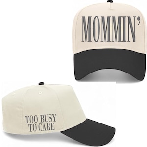 Pode incluir: Bon&eacute; de beisebol creme com aba preta. O bon&eacute; apresenta o texto "Mommin'" na frente e "Too Busy To Care" na lateral em letras cinzentas. O bon&eacute; tem um bot&atilde;o preto na parte superior.