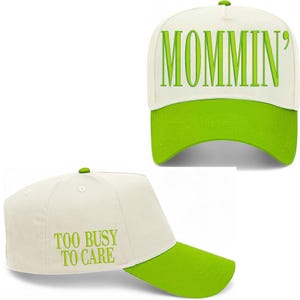 Pode incluir: Bon&eacute; de beisebol branco com aba e bot&atilde;o verdes. O bon&eacute; tem a palavra "MOMMIN'" em letras verdes na frente e "TOO BUSY TO CARE" na lateral.