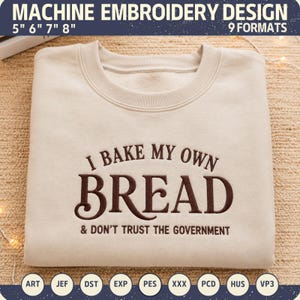 Puede incluir: Una sudadera beige de cuello redondo con bordado a máquina en marrón oscuro que dice I BAKE MY OWN BREAD & DON'T TRUST THE GOVERNMENT. El diseño está disponible en tamaños de 5, 6, 7 y 8 pulgadas en 9 formatos de archivo, incluidos ART, JEF, DST, EXP, PES, XXX, PCD, HUS y VP3.