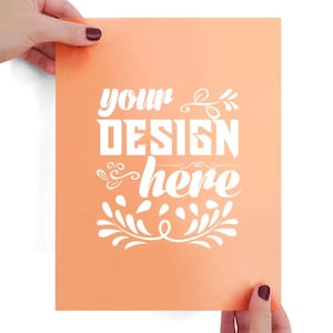 Puede incluir: Una hoja de papel rectangular de color melocotón con el texto blanco "YOUR DESIGN here" en una mezcla de fuentes en bloque y cursivas, acentuado con adornos blancos decorativos y patrones en forma de hojas en el centro.