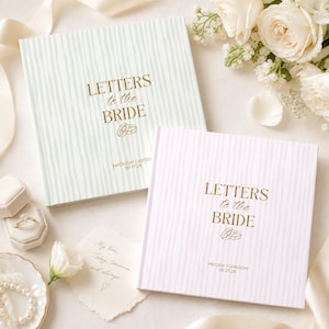 May include: Two square books with gold foil text reading LETTERS to the BRIDE, featuring personalised names and dates. One book has a light green striped cover, and the other has a light pink striped cover. Both include a small gold ring icon.