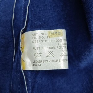 Peut inclure: Gros plan sur un tissu bleu fonc&eacute; avec une &eacute;tiquette blanche. L'&eacute;tiquette contient du texte, dont 'ART. NO. 6757806', 'FB. NO. 12', et '43774'. Le tissu semble doux.