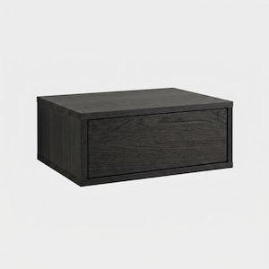 May include: A rectangular wall-mounted storage unit featuring a dark charcoal gray wood grain finish. The unit consists of a single horizontal drawer with a flat front panel and a clean, boxy frame, showcasing the natural texture of the wood.
