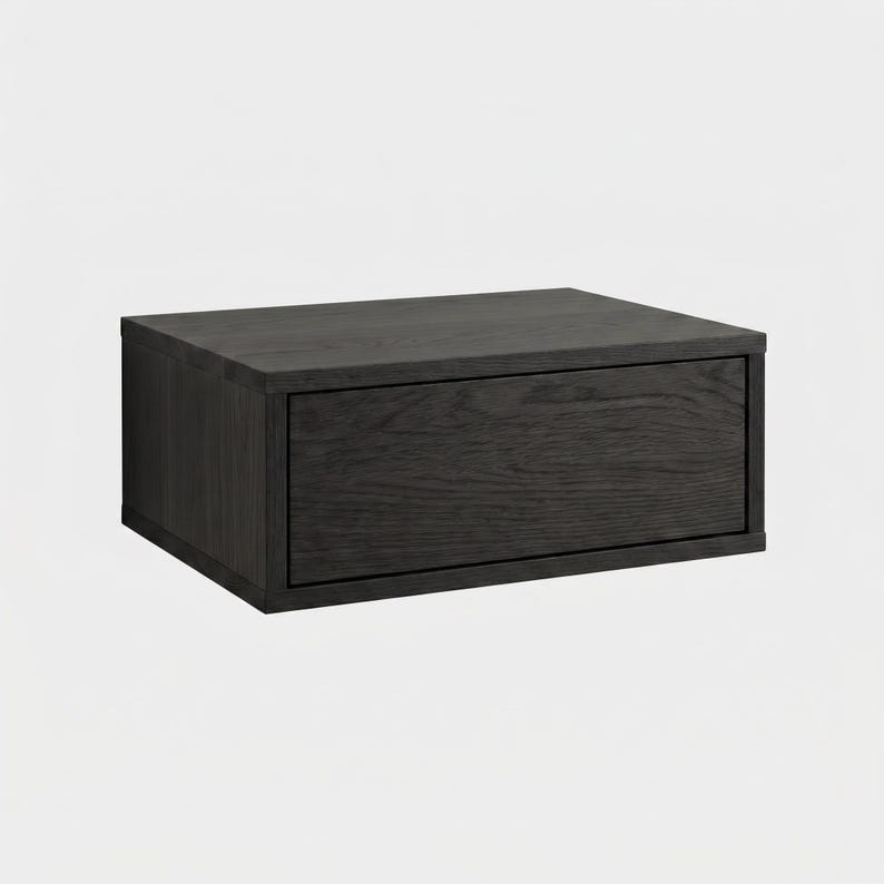 May include: A rectangular wall-mounted storage unit featuring a dark charcoal gray wood grain finish. The unit consists of a single horizontal drawer with a flat front panel and a clean, boxy frame, showcasing the natural texture of the wood.