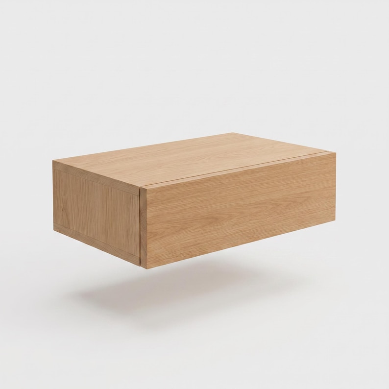 May include: A rectangular wall-mounted floating shelf unit crafted from light-toned oak wood. The piece features a clean, boxy design with a smooth, natural wood grain finish, a flat top surface, and a solid front panel with no visible hardware.