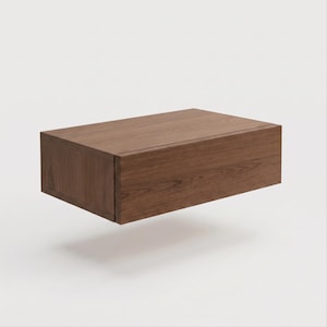 May include: A rectangular floating wall shelf constructed from dark brown wood with a visible natural grain pattern. The shelf features a clean, box-like design with a solid front panel and side edges, presenting a smooth, flat top surface.