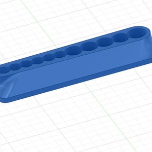 Puede incluir: Un bloque organizador azul, alargado y rectangular, que presenta una fila de diez orificios circulares empotrados en la superficie superior. El objeto tiene bordes lisos y redondeados y un perfil ligeramente cónico sobre un fondo de cuadrícula.