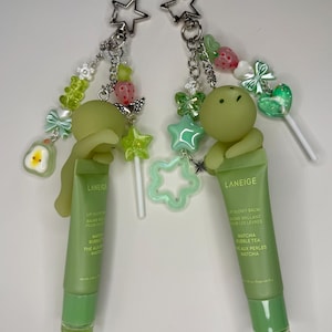 May include: Two green lip balm keychains with star-shaped charms and decorative beads. Each keychain features a tube of Laneige lip glow balm with the text "Matcha Bubble Tea". The charms include stars, strawberries, and gummy bear shapes.