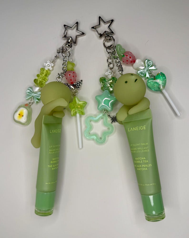 May include: Two green lip balm keychains with star-shaped charms and decorative beads. Each keychain features a tube of Laneige lip glow balm with the text "Matcha Bubble Tea". The charms include stars, strawberries, and gummy bear shapes.
