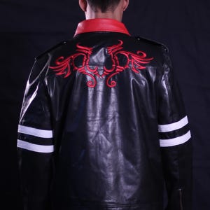 Könnte beinhalten: Schwarze Lederjacke mit rotem Kragen und roter Stickerei auf dem Rücken. Weiße Streifen auf den Ärmeln und ein Reißverschlussdetail. Ein stilvolles Oberbekleidungsstück.