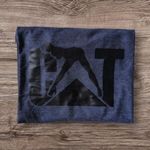 K&ouml;nnte beinhalten: Ein marineblaues T-Shirt mit einer schwarzen Grafik einer Person in Silhouette, die die Buchstaben "CAT" bildet.