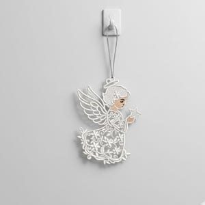 May include: White embroidered angel decoration with detailed wings, holding a star. The angel has a halo and is suspended by a silver string. The decoration is attached to a white wall hook.