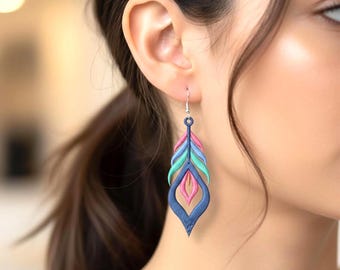 Könnte beinhalten: Ein hängender Ohrring mit einem geschichteten, federartigen Design. Der Ohrring besteht aus einem dunkelblauen Außenrahmen mit inneren Abschnitten aus leuchtend rosa, hellblauem und türkisfarbenem Stickgarn, befestigt an einem silberfarbenen Haken.