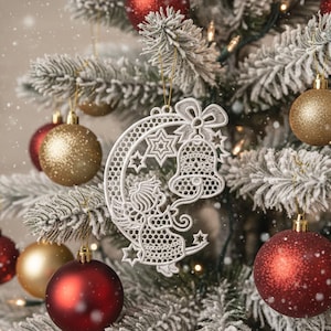 Könnte beinhalten: Ein geschmückter Weihnachtsbaum mit roten und goldenen Kugeln. Ein weißer, spitzenartiger Schmuck in Form eines Halbmonds und einer Glocke hängt am Baum. Der Baum hat gefrorene Äste und kleine Lichter.