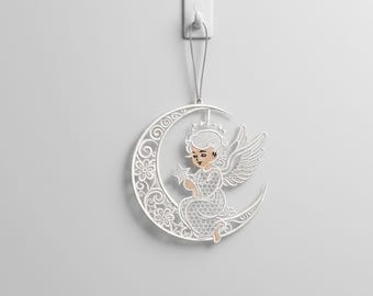 Op de afbeelding: Een wit, lasergesneden engelenornament, opgehangen aan een zilveren touwtje. De engel, met een ster, zit op een halve maan met bloemen- en wervelontwerpen. De engel heeft een kroon, vleugels en een patroonjurk.