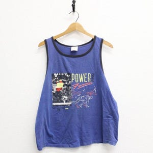 May include: A blue sleeveless vest with black trim around the neckline and armholes. The front features a graphic print of a runner with the text "POWER AND FORM" and the Spalding logo. The garment is displayed on a wooden hanger.