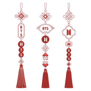 Puede incluir: Tres adornos bordados rojos con borlas. Cada adorno presenta las letras "BTS" y varios elementos decorativos. Los adornos están suspendidos de bucles y sobre un fondo blanco.