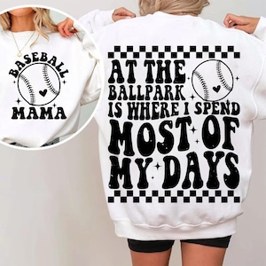 May include: White sweatshirt with black text that reads "Baseball Mama" on the front and "At the ballpark is where I spend most of my days" on the back. The back also features a black and white checkered pattern and a baseball graphic.