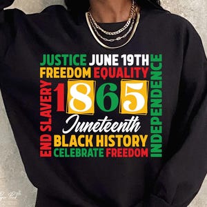 May include: Black sweatshirt with a colorful graphic design. The design includes the text "JUSTICE JUNE 19TH FREEDOM EQUALITY" and the number "1865" in a vibrant color scheme. Additional text includes "Juneteenth", "BLACK HISTORY", and "CELEBRATE FREEDOM".