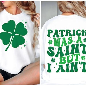 May include: White sweatshirt with a green four-leaf clover on the front and the text "Patrick was a saint but I ain't" on the back.