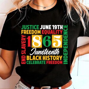 May include: Black t-shirt with a colorful graphic design. The design includes the words "JUSTICE JUNE 19TH FREEDOM EQUALITY" and "1865 Juneteenth BLACK HISTORY CELEBRATE FREEDOM". The words "END SLAVERY" and "INDEPENDENCE" are also included.