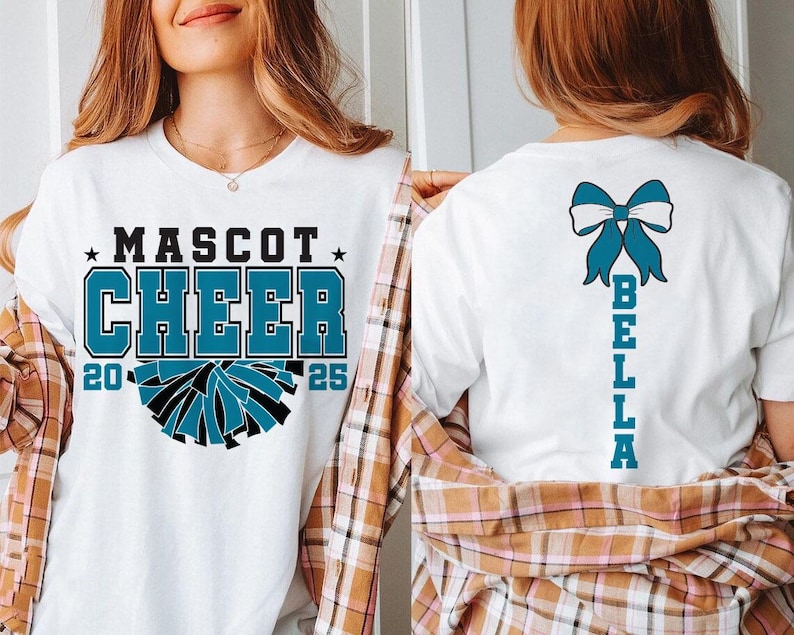May include: White t-shirt with the text "MASCOT CHEER 20 25" and a blue and black cheerleading pom-pom graphic. The back of the shirt has a blue bow with the text "BELLA" written vertically.