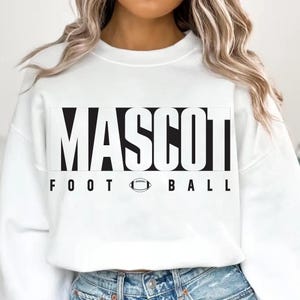 May include: White sweatshirt with the word "MASCOT" in large, bold, black letters. Below, the words "FOOT BALL" are printed in black, with a football graphic in the center. The sweatshirt is a casual style.