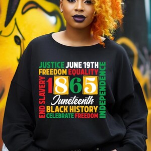 May include: Black sweatshirt with the words "JUSTICE JUNE 19TH FREEDOM EQUALITY 1865 Juneteenth BLACK HISTORY CELEBRATE FREEDOM" in green, red, and yellow. The sweatshirt is a crew neck style.