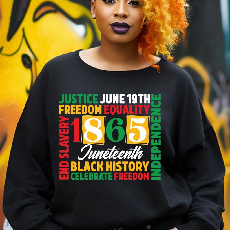 May include: Black sweatshirt with the words "JUSTICE JUNE 19TH FREEDOM EQUALITY 1865 Juneteenth BLACK HISTORY CELEBRATE FREEDOM" in green, red, and yellow. The sweatshirt is a crew neck style.