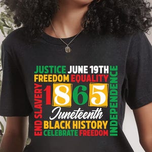 May include: Black t-shirt with a colorful graphic design. The design includes the words "Justice," "Freedom," "Equality," "1865," "Juneteenth," "Black History," and "Celebrate Freedom."