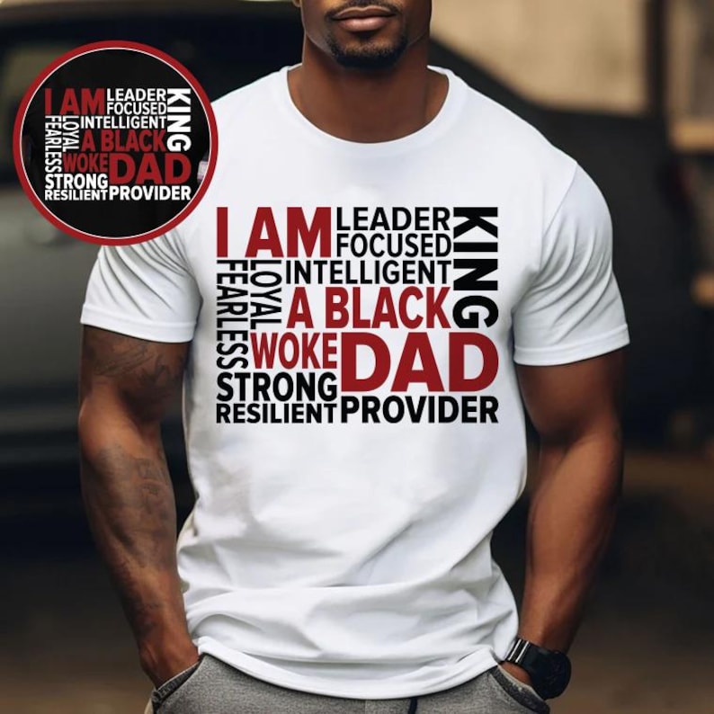 Op de afbeelding: Wit t-shirt met de tekst "I AM A BLACK DAD" in een moderne lettertype. Het ontwerp bevat woorden als "Leader", "Focused" en "Strong". Een cirkelvormig ontwerp met dezelfde tekst staat linksboven.
