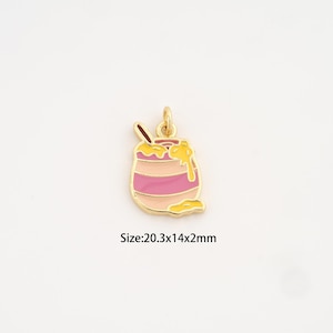 Puede incluir: Un charm dorado con forma de tarro de miel con esmalte rosa y amarillo. El charm tiene una cuchara dentro y miel goteando. Tamaño: 20,3x14x2mm.