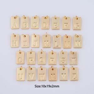 May include: Gold-colored metal alphabet letter charms. Each charm is a small rectangular tag with a raised letter. The charms are arranged in alphabetical order from A to Z. Size: 10x19x2mm.