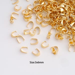 May include: A large collection of gold-coloured metal pinch bails for jewellery making. Each U-shaped component features two small prongs at the ends for securing pendants. The text Size:3x6mm is printed in black at the bottom of the image.