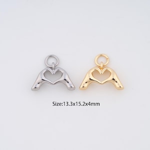 May include: Two heart-shaped charms, one silver-colored and one gold-colored, with a loop at the top for attaching to a chain or bracelet. The charms are approximately 0.5 x 0.6 x 0.1 inches in size. The text "Size: 13.3x15.2x4mm" is below the charms.