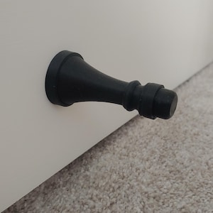 May include: Black doorstop shaped like a rounded, tapered cone with a textured surface.