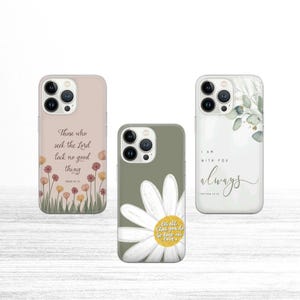 May include: Three phone cases with inspirational quotes. One case is light pink with a floral design and the text "Those who seek the Lord lack no good thing." Another is olive green with a daisy and the text "Let all that you do be done in love." The third is white with a botanical design and the text "I am with you always."