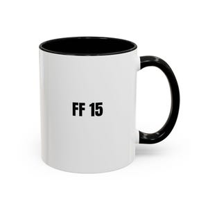 Puede incluir: Taza de cerámica blanca con interior y asa negros. La taza presenta el texto "FF 15" en letras negras en negrita en la parte delantera. Adecuada para bebidas frías o calientes.
