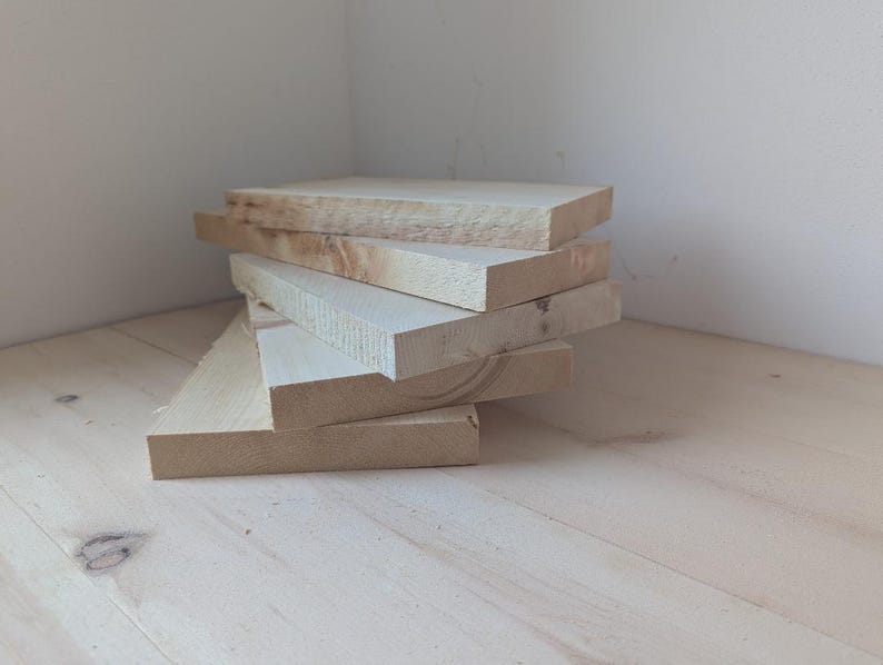 May include: A stack of five unfinished wooden boards, likely for crafting or woodworking projects.