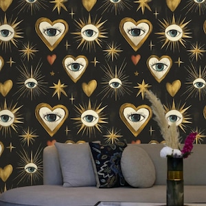 May include: Black wallpaper featuring a repeating pattern of gold-framed hearts with eyes, sunburst eyes, gold stars, and red hearts. A gray sofa with decorative pillows and a coffee table are in the foreground.