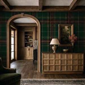 Può includere: Una stanza con carta da parati a quadri verde scuro, un arco in legno e un mobile in legno. Un quadro incorniciato e una lampada con paralume beige sono sul mobile. L'ambiente è caldo e tradizionale.