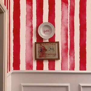 Könnte beinhalten: Eine Wand mit einem rot-weiß gestreiften Aquarelldesign. Auf der Wand ist ein weißer Teller mit dem Wort "Appetite" in roter Schrift angebracht. Darunter befindet sich ein gerahmter Vintage-Druck mit dem Text "9. Place Pigalle" und "P. Sescau Photographe."